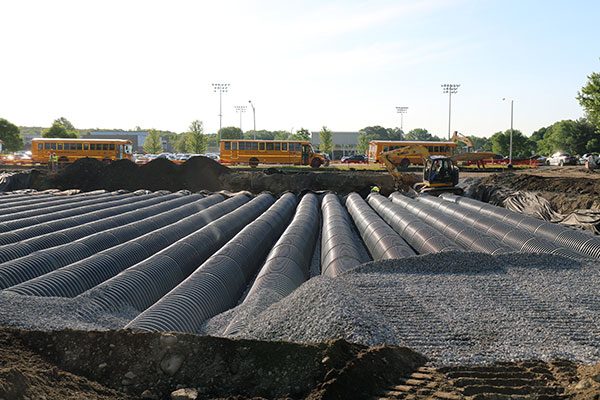 Underground corrugated pipes with school buses in background
